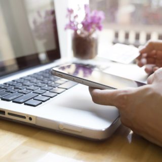 Woman using laptop and mobile phone to online shopping and pay by credit card. Mobile focus. Vintage tone, Retro filter effect, Soft focus, Low light.(selective focus)
