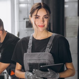 Auto service, repair, maintenance concept. Mechanic checks the car at the service station. Charming woman and bearded engineer use tablet check car battery