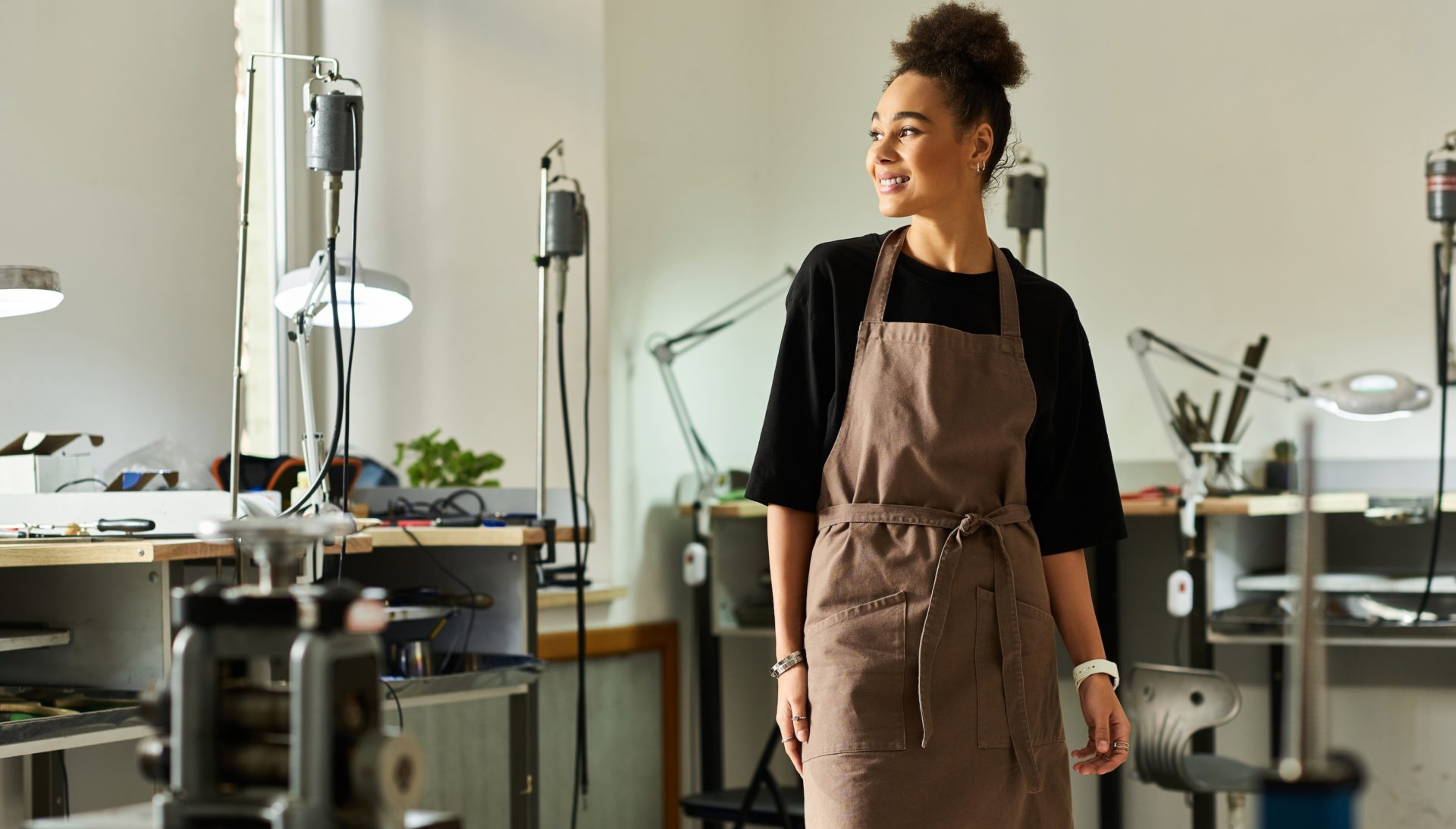 A talented woman stands confidently in a well equipped workshop, surrounded by tools.