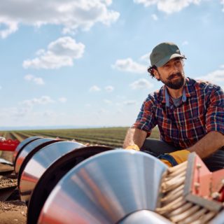 Pensive agronomist setting up disc harrows on a tractor while plowing the land.