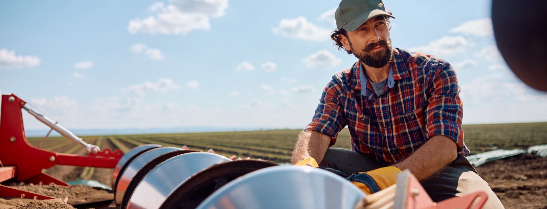 Pensive agronomist setting up disc harrows on a tractor while plowing the land.