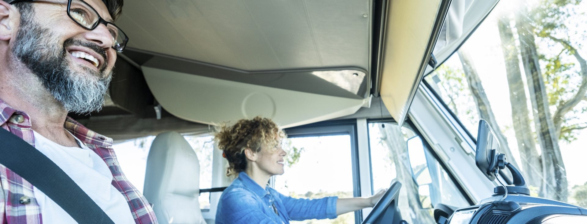 One woman driving modern rv camper van vehicle with happy man on her side as passenger. Happy couple of tourist enjoy travel lifestyle vanlife together. Rental transport and vacation concept holiday